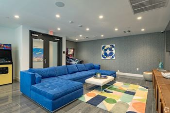 Our lounge and gaming zone with a blue sofa and arcade games at Hollywood Heights on the Boulevard Luxury Apartments in Hollywood, FL